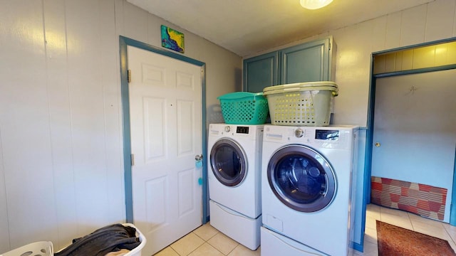 laundry area featuring light tile patterned floors, cabinet space, and washing machine and clothes dryer