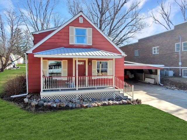 bungalow with a front lawn, a porch, concrete driveway, metal roof, and an attached carport