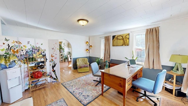 home office featuring light wood-style flooring and arched walkways