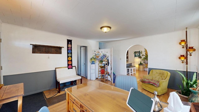 office with arched walkways, wainscoting, and light wood finished floors