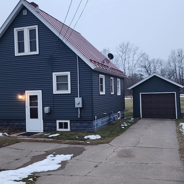 view of side of home with an outbuilding, driveway, a detached garage, and metal roof