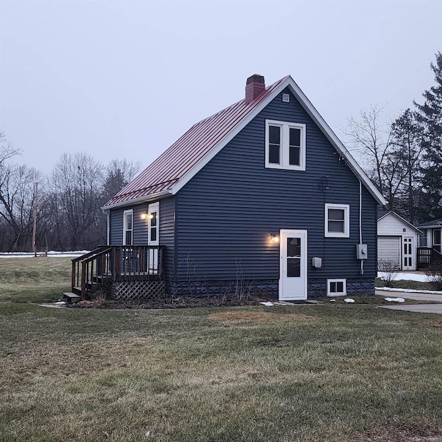 rear view of property with metal roof, a lawn, and a chimney