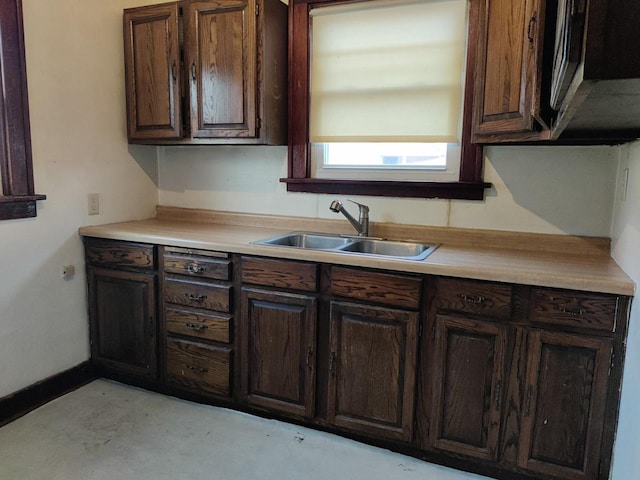 kitchen featuring dark brown cabinets, light countertops, and a sink