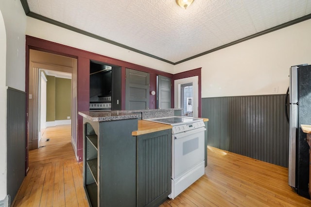 kitchen with a wainscoted wall, electric stove, open shelves, freestanding refrigerator, and light wood finished floors