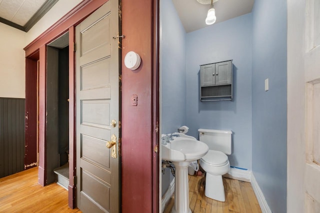 bathroom featuring baseboards, ornamental molding, hardwood / wood-style flooring, a baseboard heating unit, and toilet