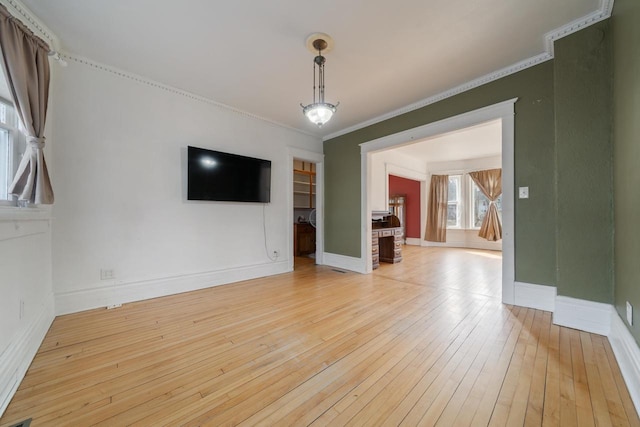 unfurnished living room with light wood-type flooring, baseboards, and crown molding