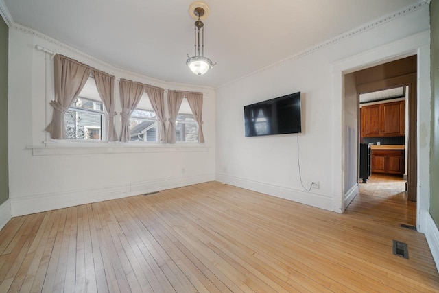 spare room with visible vents, baseboards, light wood-style floors, and crown molding