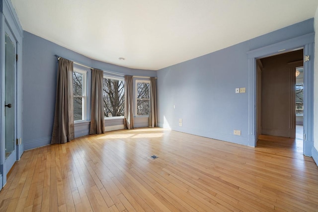 unfurnished room featuring baseboards and light wood-style floors