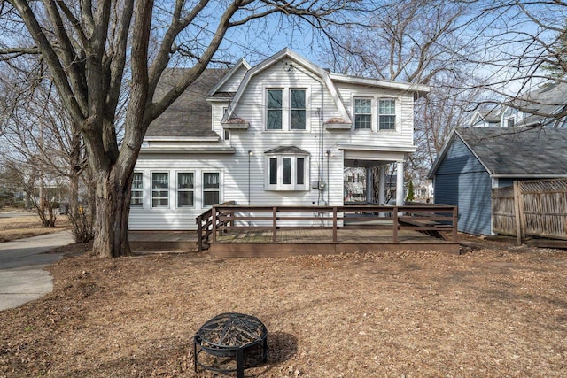 view of front of house with a gambrel roof, fence, an outdoor fire pit, roof with shingles, and a wooden deck