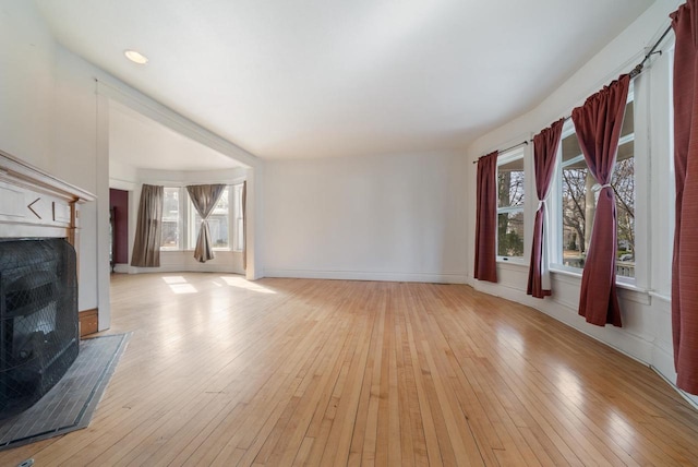 living room with light wood-style flooring, a fireplace, and a healthy amount of sunlight