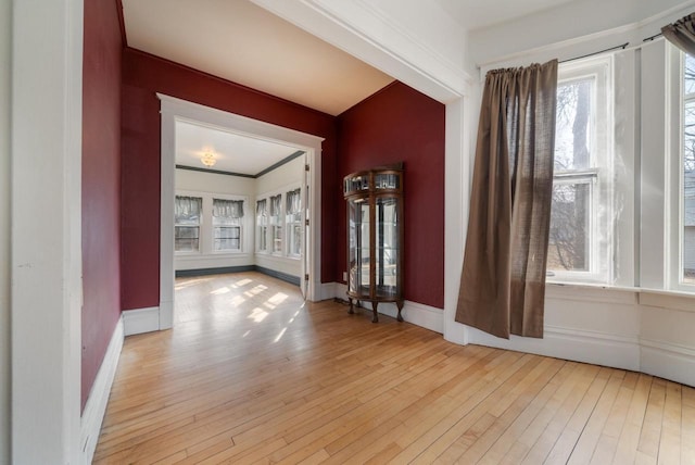 empty room featuring ornamental molding, baseboards, and hardwood / wood-style floors