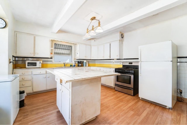 kitchen featuring beamed ceiling, light wood-style flooring, tile countertops, white appliances, and white cabinets