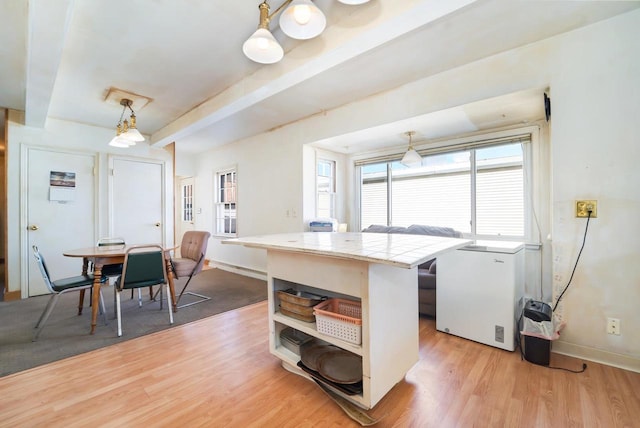 kitchen featuring open shelves, light wood-style floors, refrigerator, and tile counters