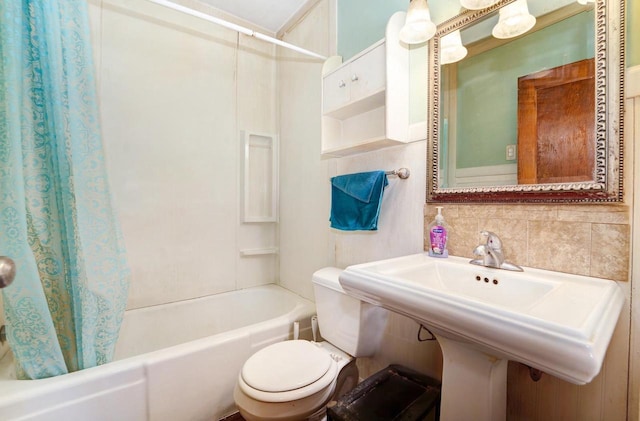 bathroom featuring a sink, shower / bath combo with shower curtain, backsplash, and toilet