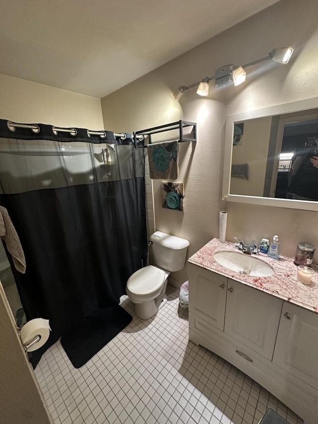 bathroom with tile patterned flooring, a shower stall, vanity, and toilet