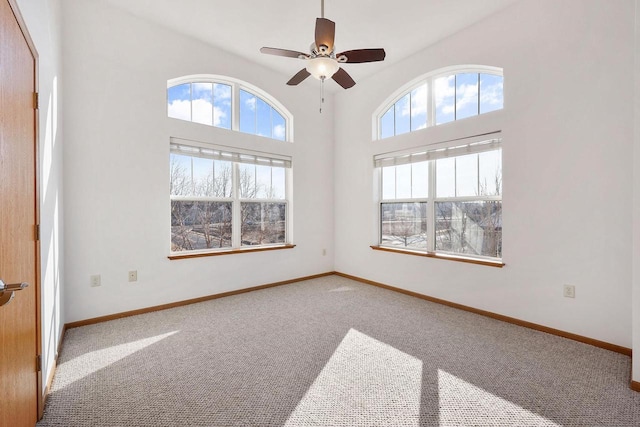 spare room featuring carpet flooring, a ceiling fan, baseboards, and a wealth of natural light