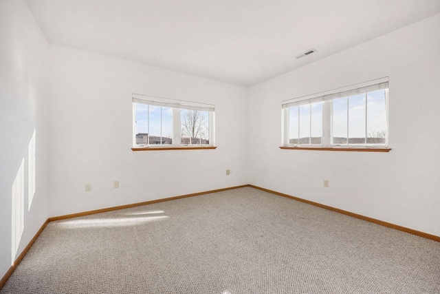 carpeted spare room featuring baseboards and visible vents