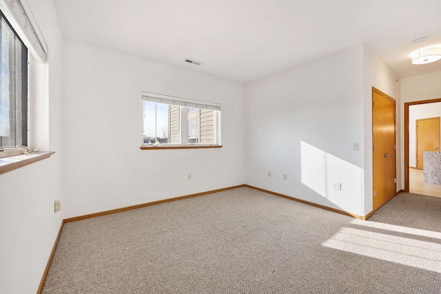 carpeted empty room with visible vents and baseboards