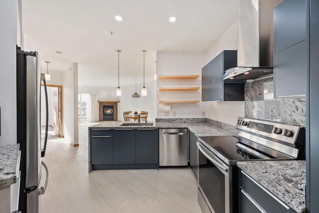 kitchen featuring stainless steel appliances, light stone countertops, modern cabinets, and wall chimney range hood