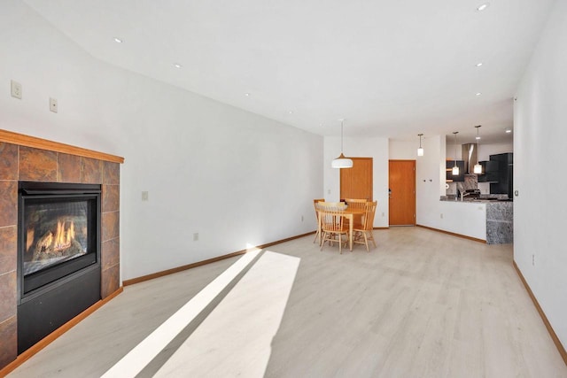 living room with light wood-type flooring, baseboards, and a fireplace