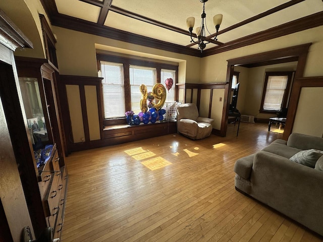 living area with hardwood / wood-style floors, a chandelier, coffered ceiling, and ornamental molding