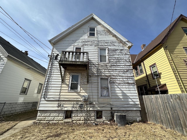 back of property featuring a balcony, central AC, and fence