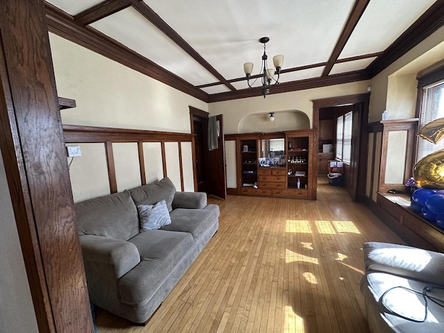 living room with light wood finished floors, coffered ceiling, crown molding, and an inviting chandelier