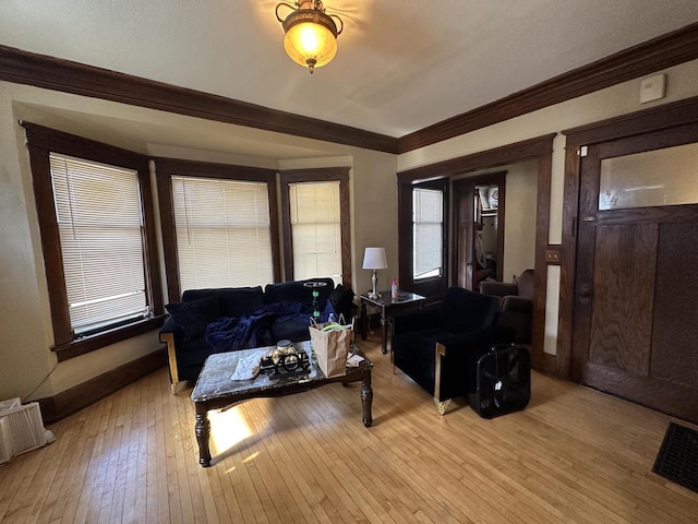 living room featuring crown molding, light wood-style flooring, and visible vents