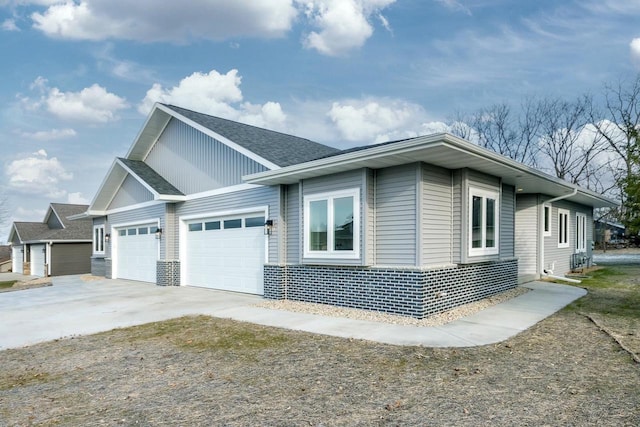 view of side of home with concrete driveway, an attached garage, and a shingled roof