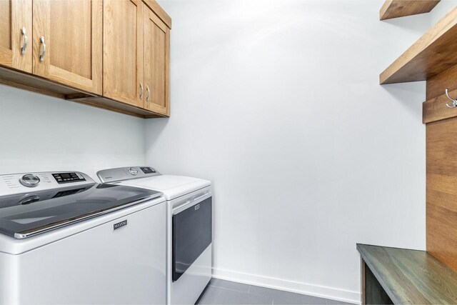 laundry area featuring baseboards, cabinet space, tile patterned flooring, and washer and clothes dryer