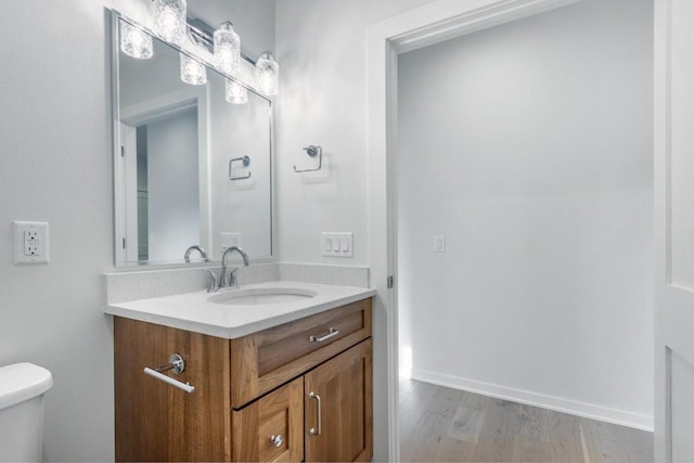 half bath with baseboards, toilet, wood finished floors, and vanity