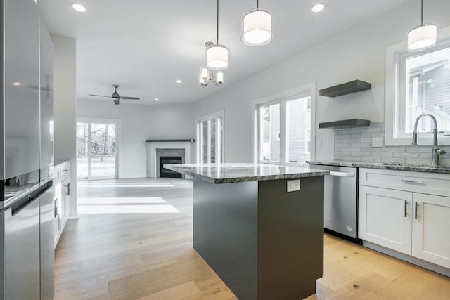 kitchen featuring a sink, white cabinets, light wood-style floors, and stainless steel dishwasher