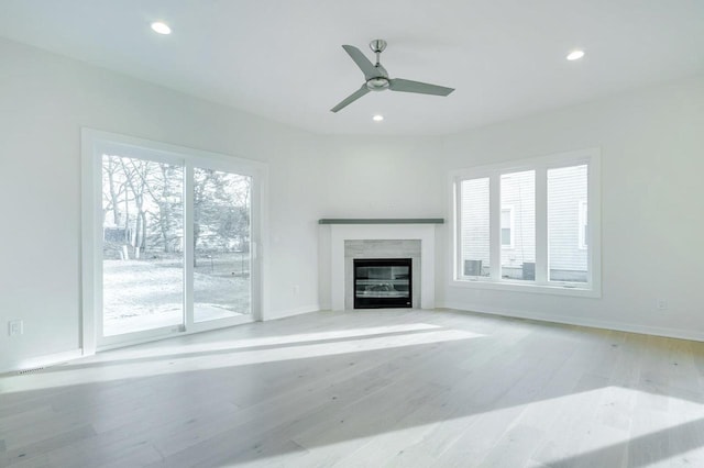 unfurnished living room with a glass covered fireplace, recessed lighting, baseboards, and wood finished floors