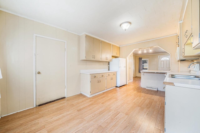 kitchen featuring light wood-type flooring, visible vents, a sink, freestanding refrigerator, and light countertops