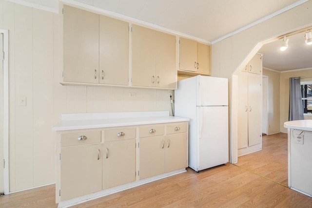 kitchen with light wood finished floors, ornamental molding, light countertops, and freestanding refrigerator