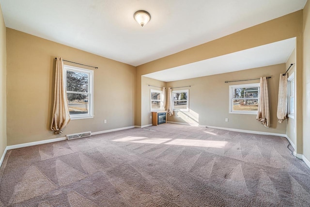 spare room featuring carpet, visible vents, and baseboards