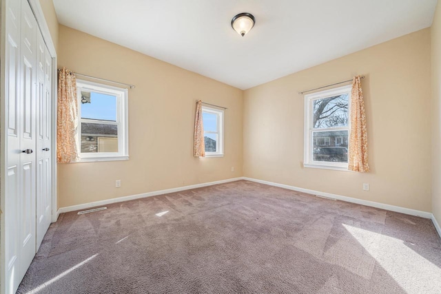 carpeted empty room with visible vents and baseboards