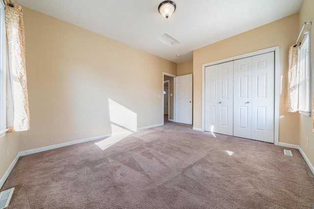 unfurnished bedroom featuring a closet, visible vents, baseboards, and carpet