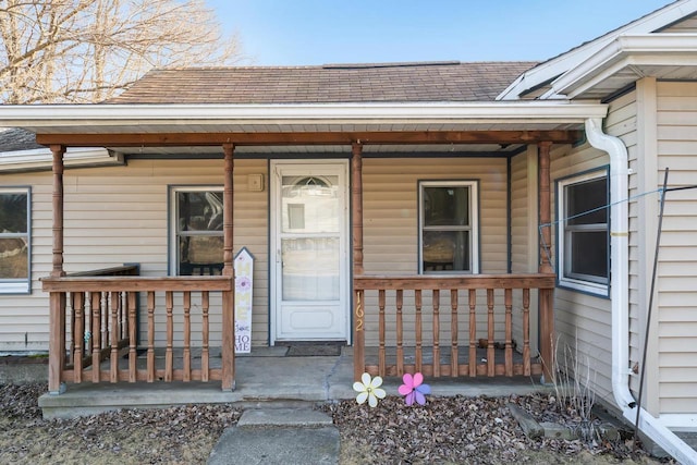 entrance to property featuring roof with shingles and covered porch