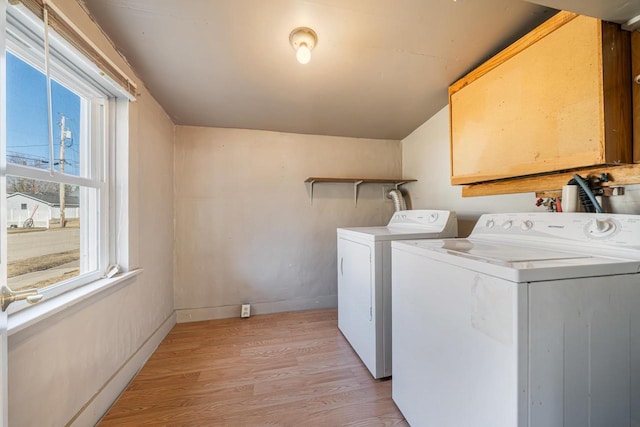 clothes washing area featuring washer and dryer, baseboards, light wood-style flooring, and laundry area