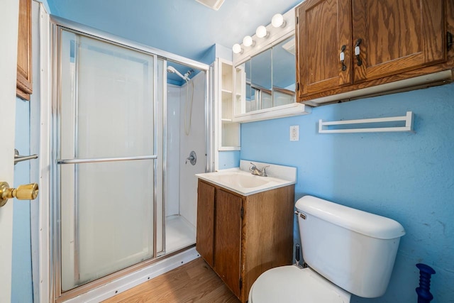 full bathroom featuring a shower stall, toilet, vanity, and wood finished floors