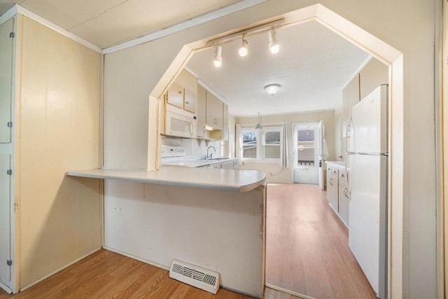 kitchen with white appliances, visible vents, light wood-style flooring, ornamental molding, and a sink