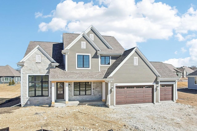 view of front of property featuring stone siding, driveway, and a shingled roof