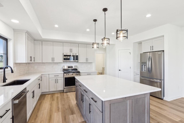 kitchen with a sink, tasteful backsplash, a kitchen island, stainless steel appliances, and light wood-style floors