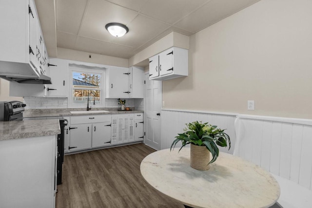 kitchen with a wainscoted wall, stainless steel range with electric stovetop, light countertops, and a sink