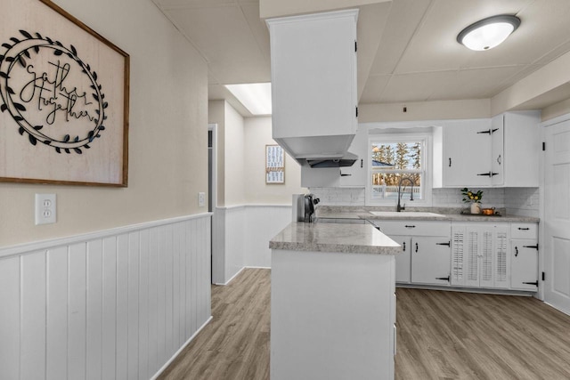 kitchen featuring a sink, stove, light countertops, light wood-style floors, and wainscoting