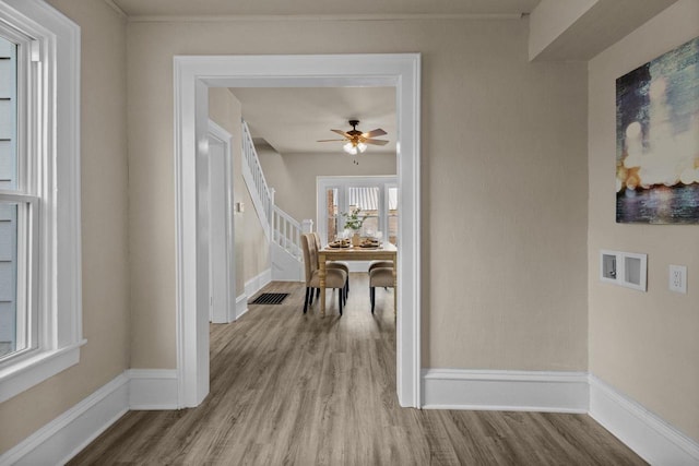 hallway featuring visible vents, baseboards, and wood finished floors