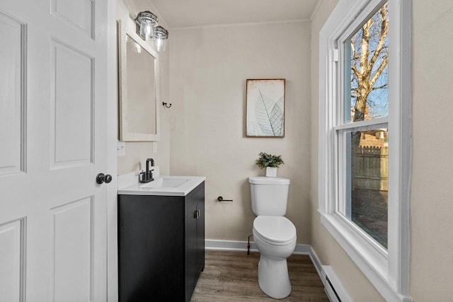 bathroom featuring vanity, wood finished floors, baseboards, a baseboard heating unit, and toilet