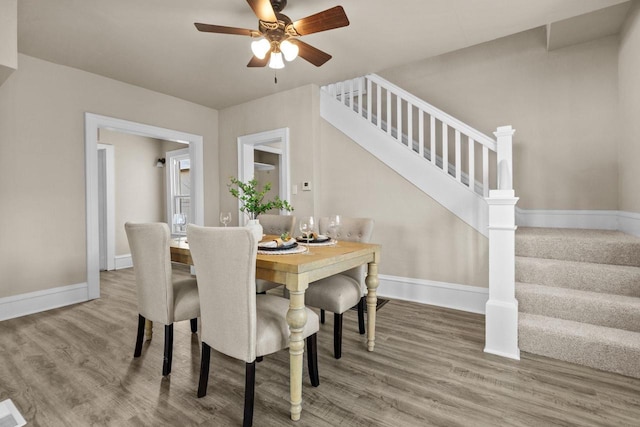 dining space featuring ceiling fan, stairway, baseboards, and wood finished floors