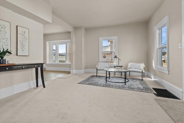 living area featuring a wealth of natural light, visible vents, baseboards, and carpet